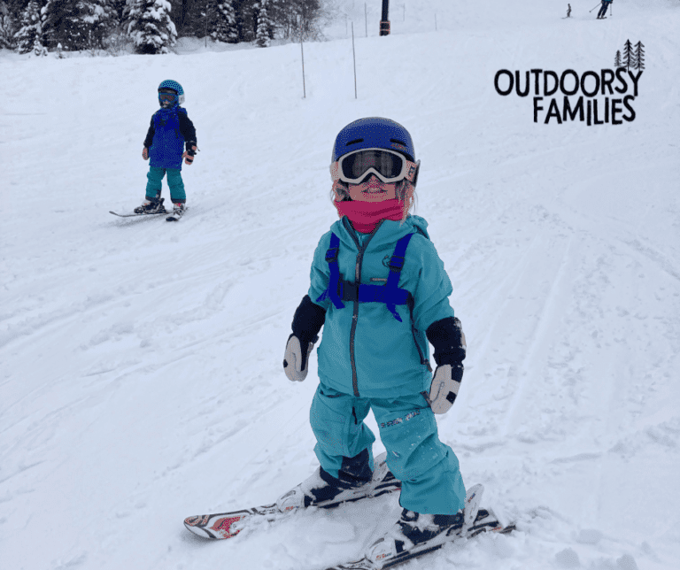 young girl skiing in Shred Dog ski gear. Wearing blue jacket and pants with purple helmet.