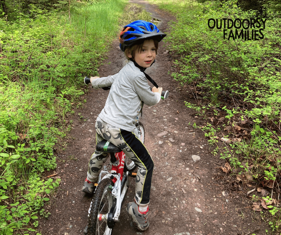 young boy rides bike on a dirt trail
