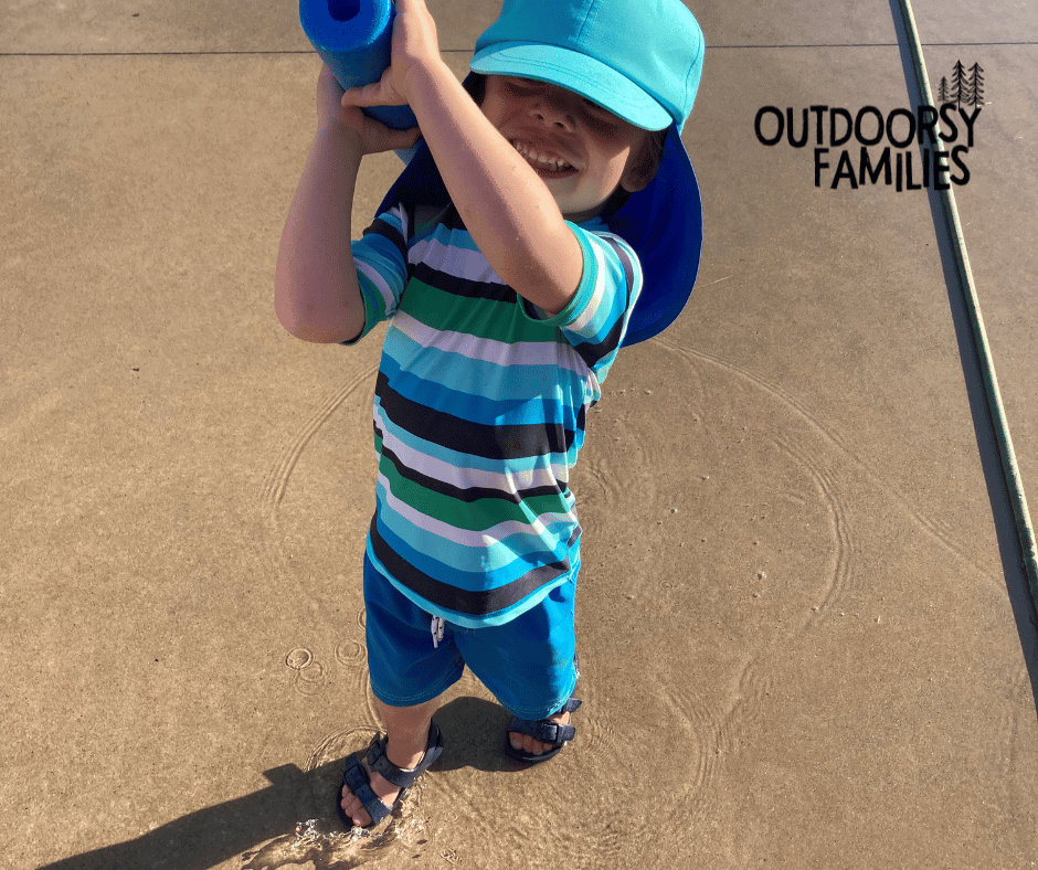 boy playing in puddles with pool noodle