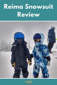 Two kids skiing with snowsuits on. One is a black snowsuit and one is a blue pattern snowsuit